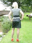 Clothed female with blonde hair shows off her red pumps in nylons on a bench