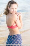 Adorable teen Faina Bona gets naked on the beach before oiling her cute pussy