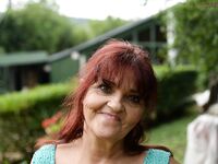 Redhead granny Livia lifts her blue dress up and reveals big natural tits