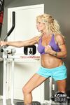 Blonde female bodybuilder shows off her nude body against punching bag