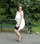 Thick woman in glasses shows off her stiletto heels on a park bench