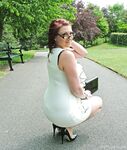 Thick woman in glasses shows off her stiletto heels on a park bench
