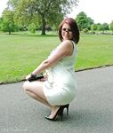 Thick woman in glasses shows off her stiletto heels on a park bench