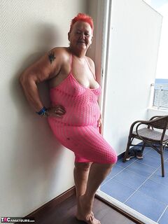 Fat nan with short red hair finger spreads her pussy on oceanside balcony